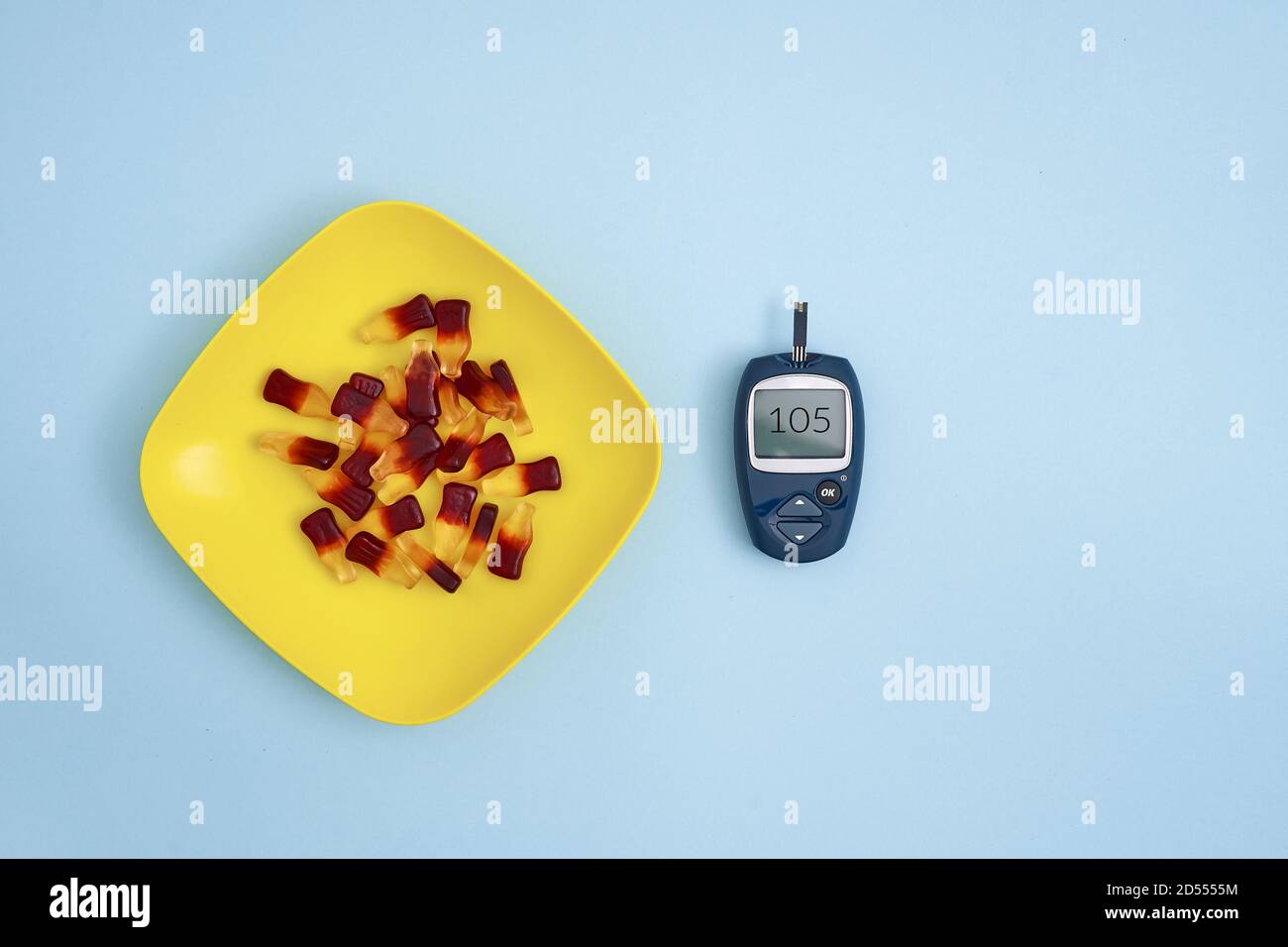 Top view of glucose meter and sweet jelly candies on blue background