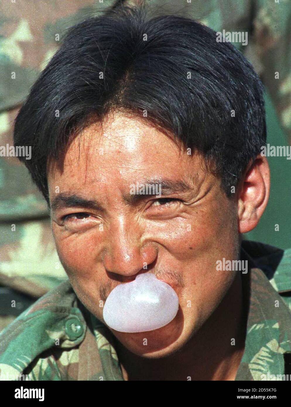 An Indian soldier blows bubble gum at a 