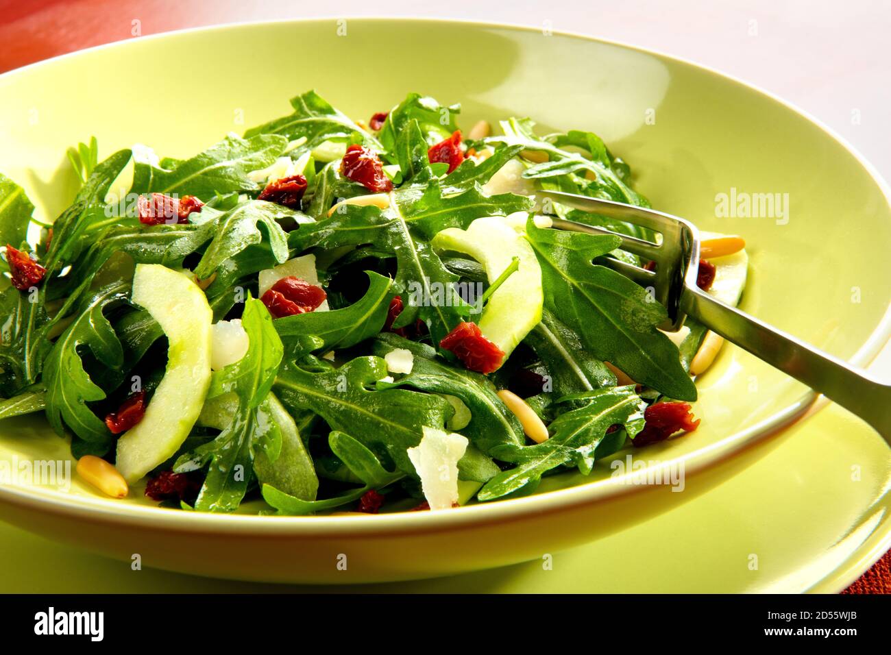 Rohkost, Salat italienischer Art mit Rucola, Gurke, getrockneten Tomaten und Pinienkernen. Stock Photo