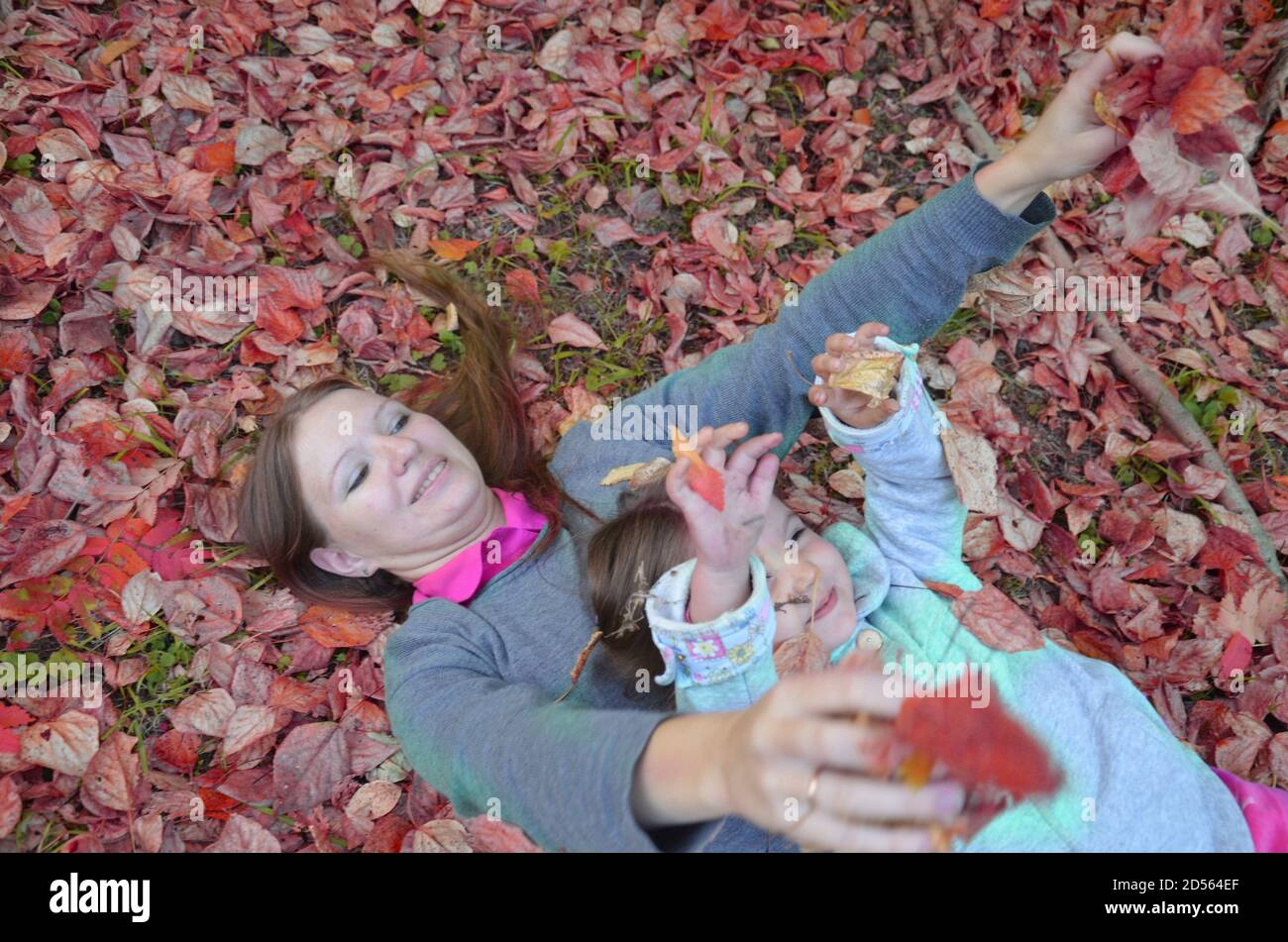 Young mother and her toddler girl have fun in autumn park Stock Photo ...