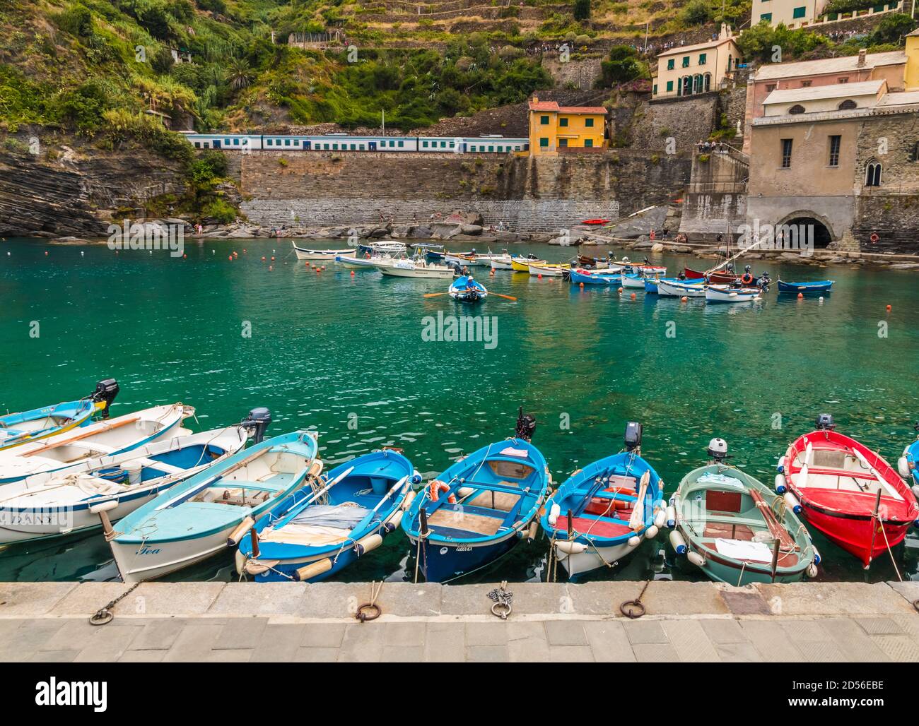 Lovely view of the port of Vernazza in the Cinque Terre coastal area. Small boats, floating on shallow turquoise water, are tied up to the pier and in... Stock Photo