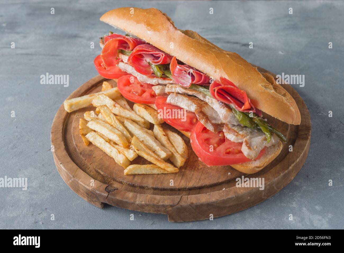 Sandwich Serranito typical in Andalusia with ham, gren pepper and grilled pork loin Stock Photo