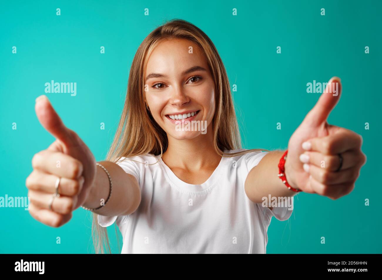 Portrait of a cheerful young woman showing thumbs up sign Stock Photo ...