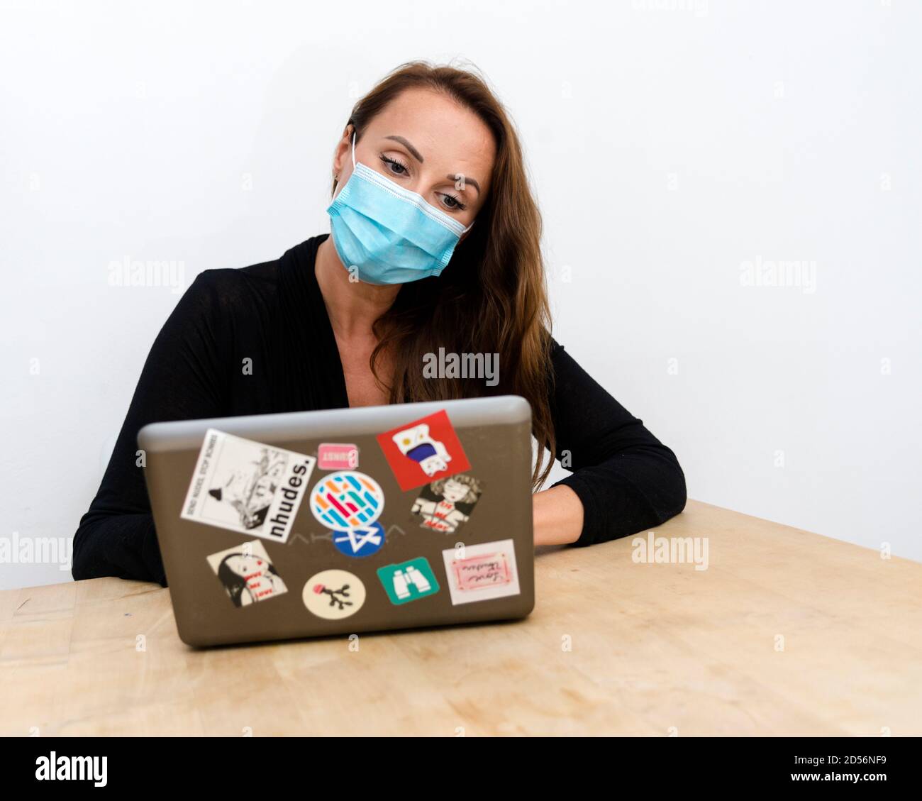 Woman working on a laptop while wearing a protective face mask Stock Photo