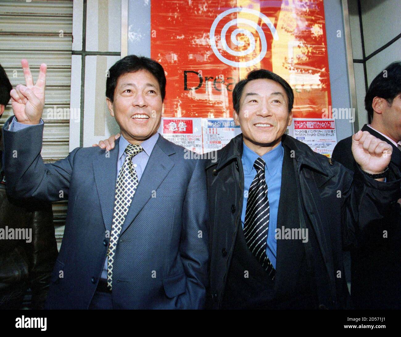 Sega Enterprises President Shoichiro Irimajiri (R) smiles as he and Sega Corporate Vice President Hidekazu Yukawa, wait for a computer game specialty shop to open for the start of sales of Sega's new Dreamcast game player in Tokyo's Akihabara electronics district November 27. The game player hit store shelves in Japan with a fanfare as the "PlayStation killer". Sega hopes that the new 128-bit, Internet-capable games player, will help it win back its lost market share.  ES/TAN/KM Stock Photo
