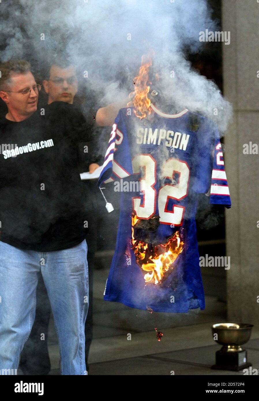 Protester Doug McBurney (L) holds a recently auctioned Buffalo Bills jersey  worn by O.J. Simpson, purchased by Denver talk show host Bob Enyart (C),  during a public burning of Simpson memorabilia at