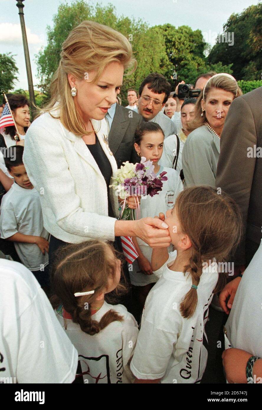 Queen Noor of Jordan touches a young girl on the cheek as she pauses to  talk with the child during the 