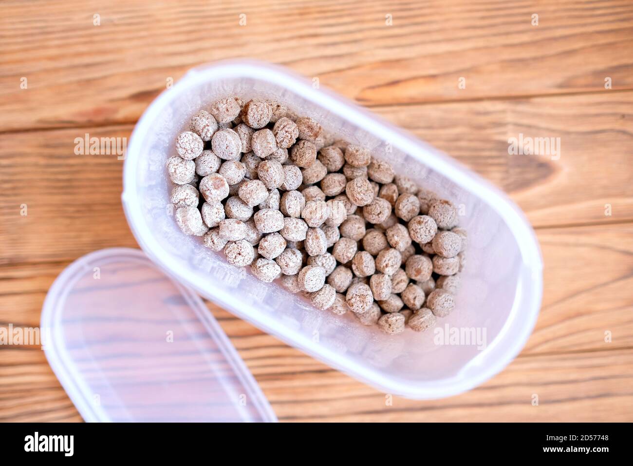 Bran in a plastic container. Dry edible balls. Wood background Stock Photo