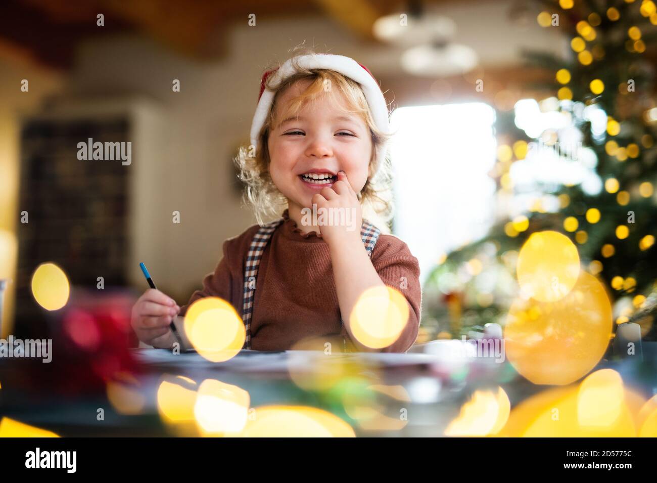 Portrait of small girl indoors at home at Christmas, painting pictures. Stock Photo