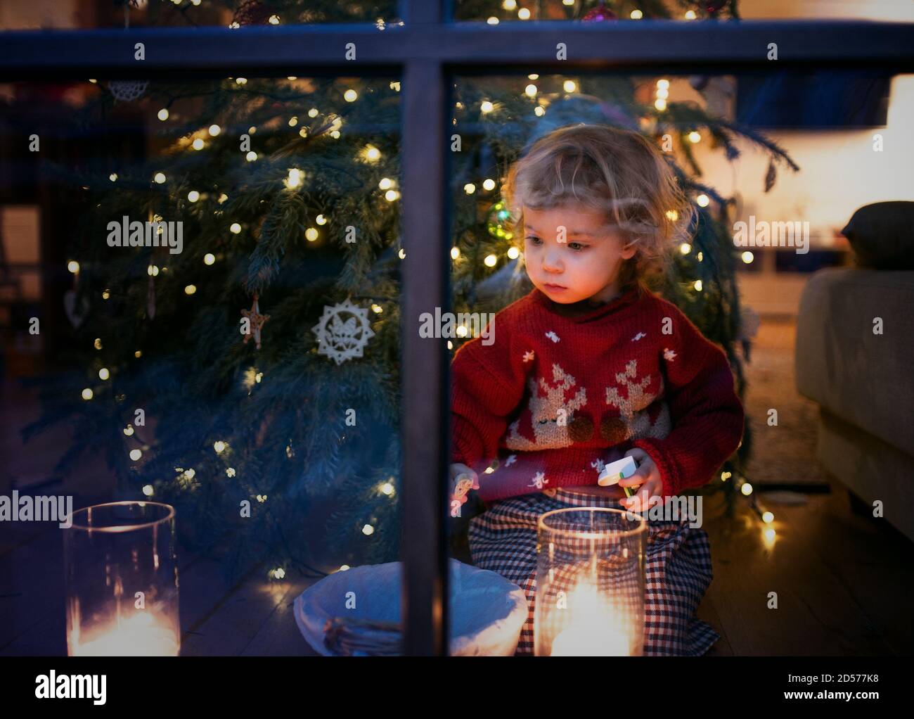 Portrait of small girl indoors at home at Christmas, playing. Stock Photo