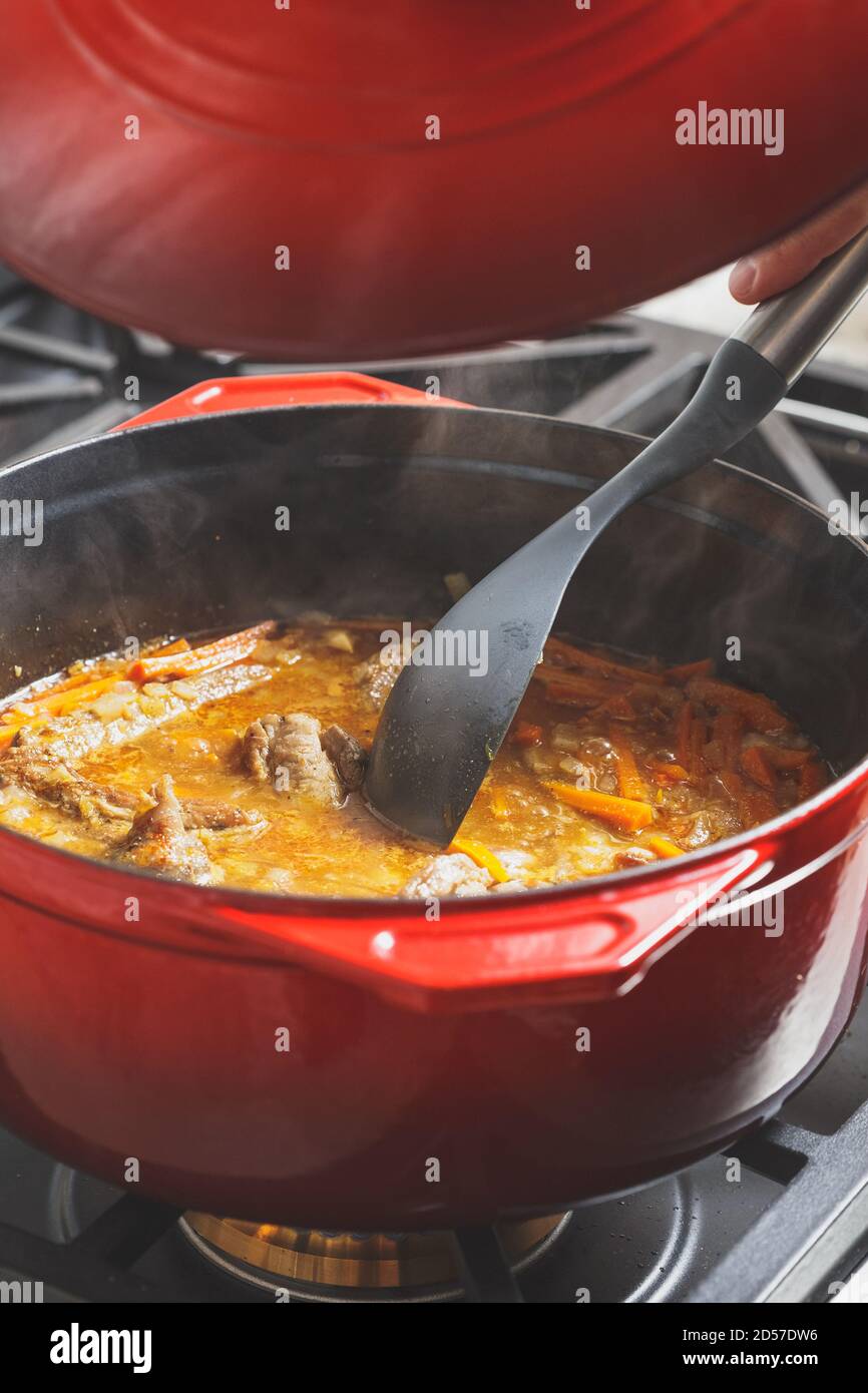 Pilaf cooking process at home. Putting cover on the red cast iron dutch