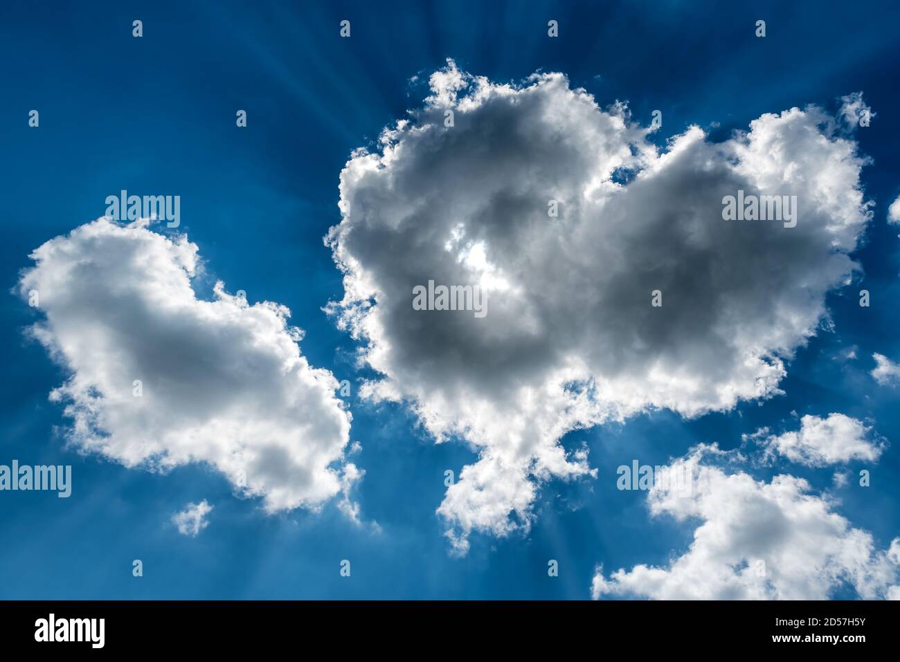 White cumulus clouds and a blue sky with sun rays Stock Photo - Alamy