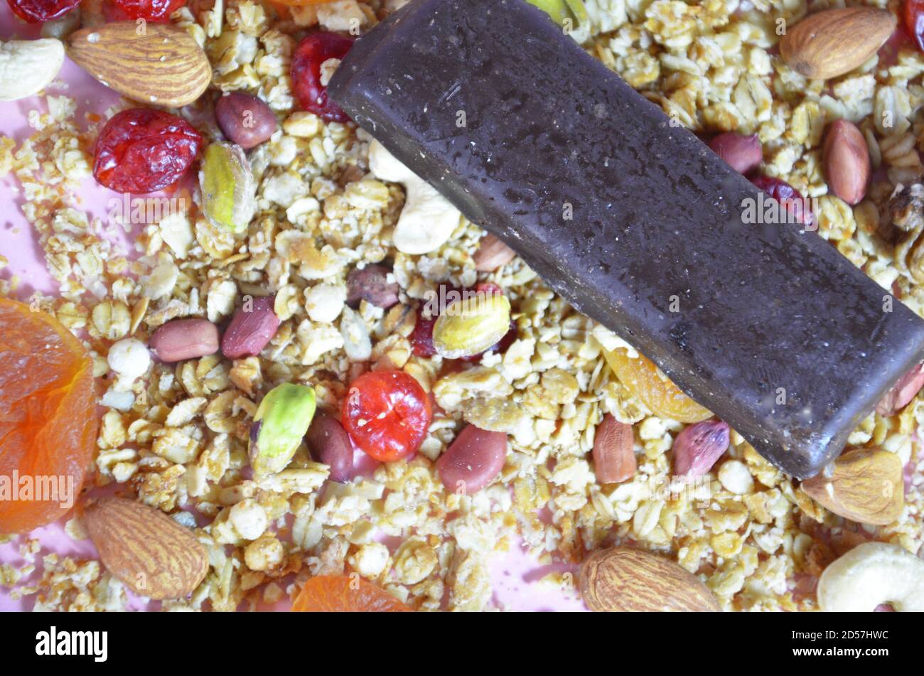 Granola bars, muesli bars or energy bars with oats, dates and nuts on white pink background, close up. Snack for yoga, fitness and sports people Stock Photo