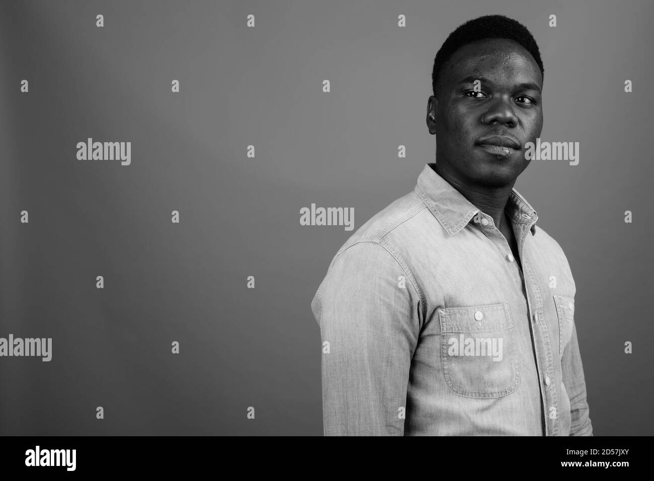 Young African man wearing denim shirt against gray background Stock Photo