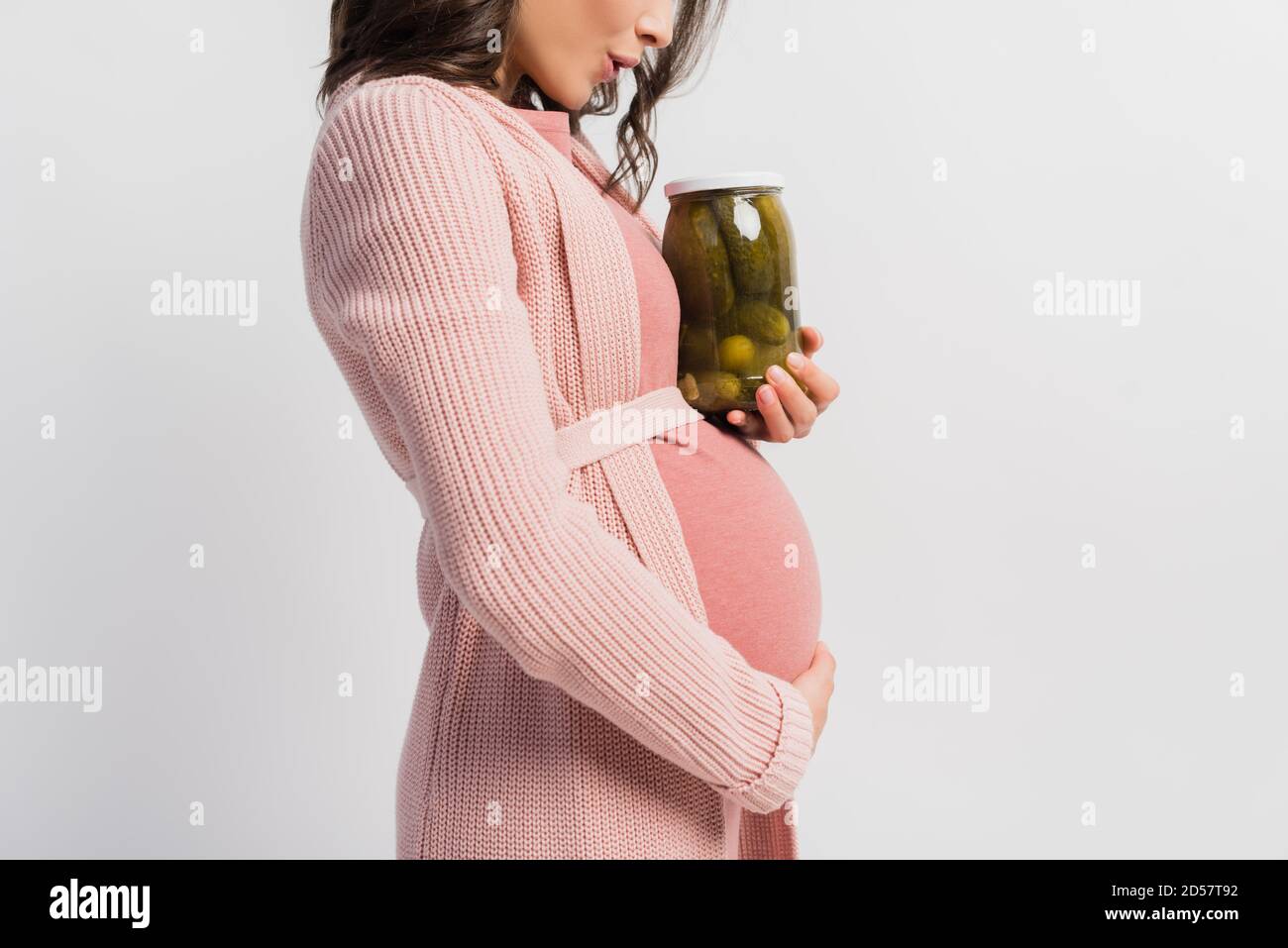 partial view of surprised and pregnant woman holding jar with pickled