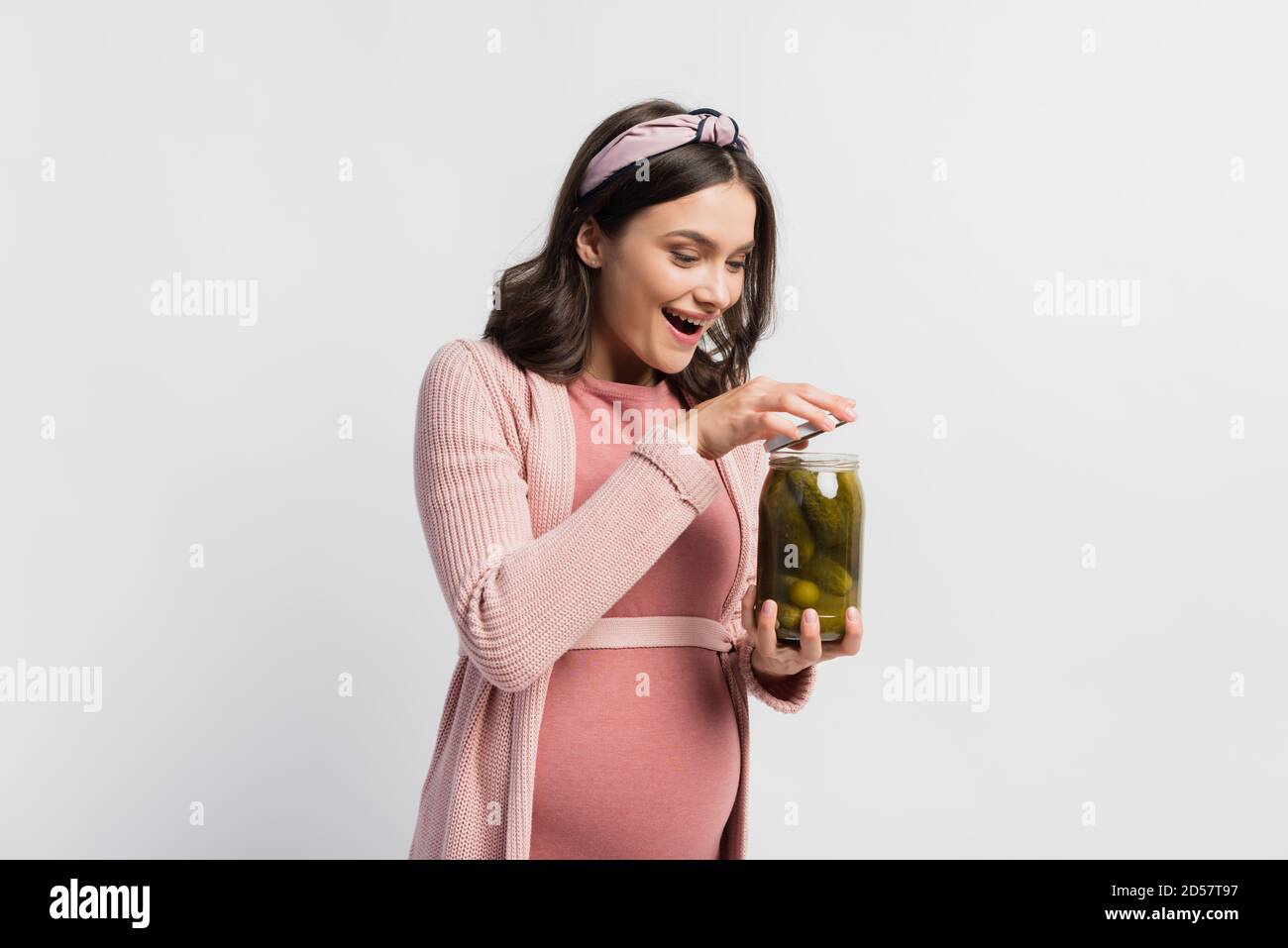 excited and pregnant woman opening jar with sour and pickled cucumbers