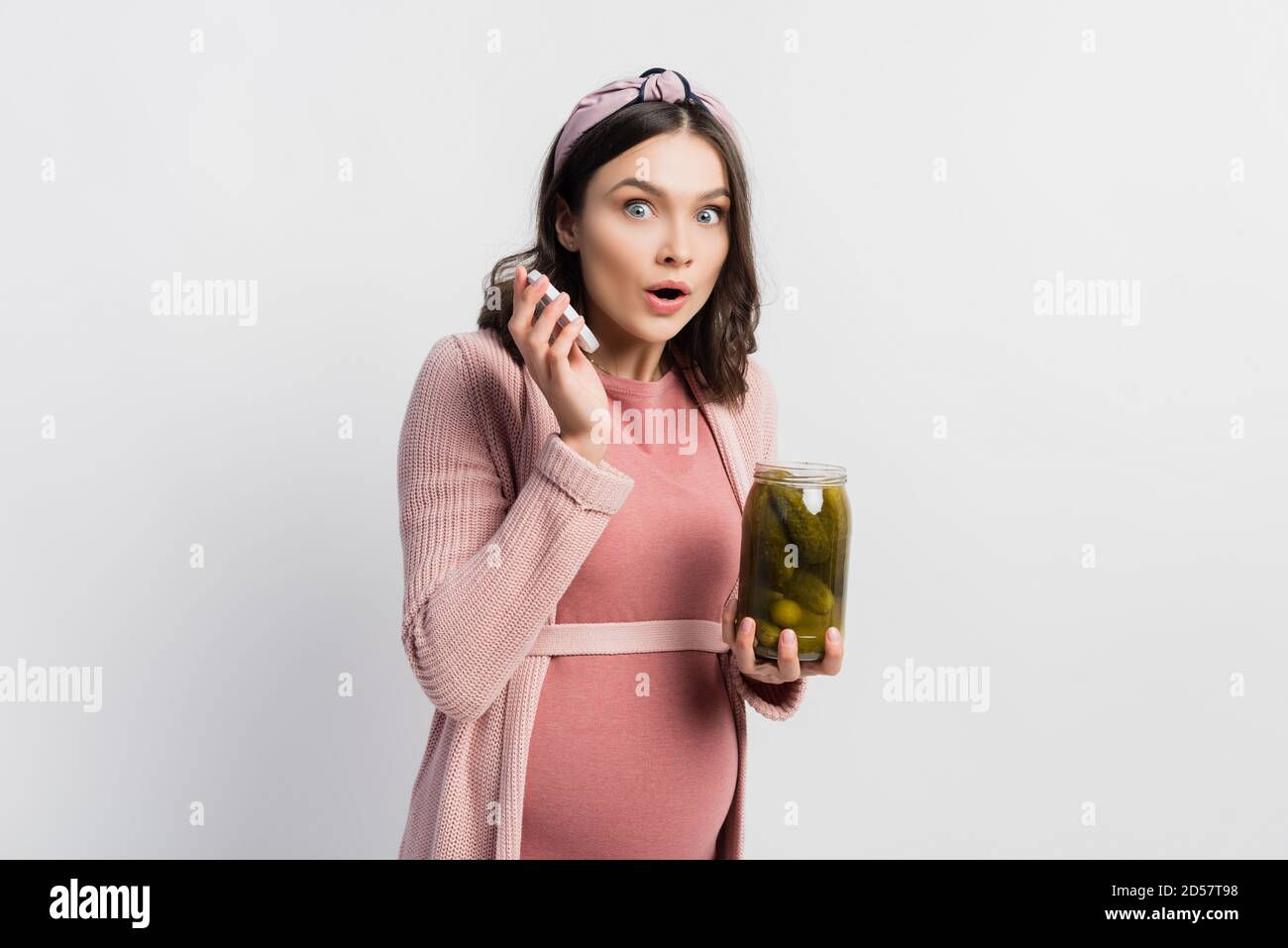 surprised and pregnant woman holding jar with pickled cucumbers on