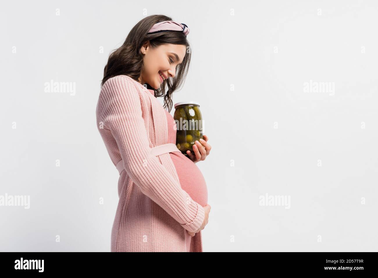 side view of pleased and pregnant woman holding jar with pickled