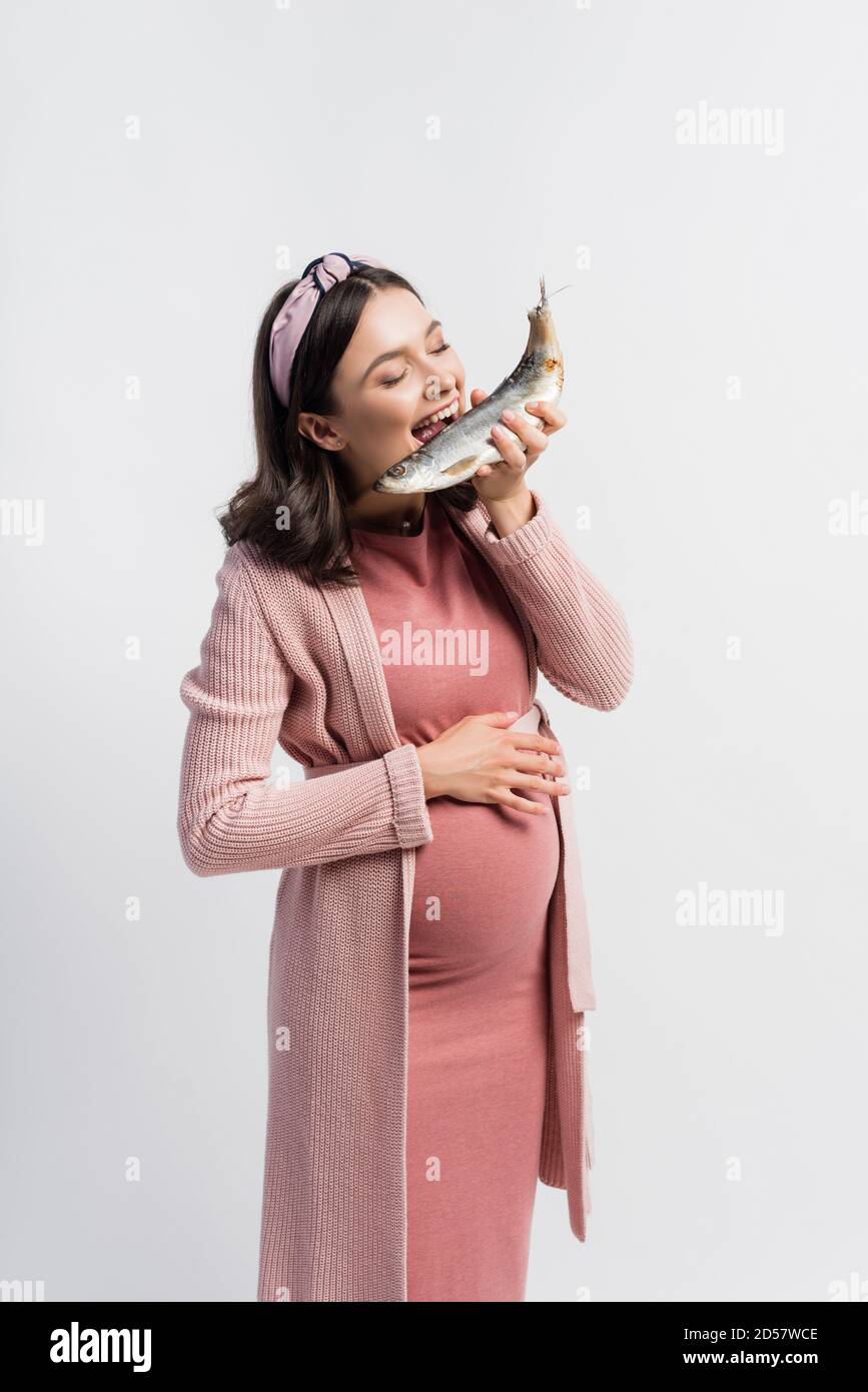 pregnant woman with closed eyes and open mouth eating dried fish