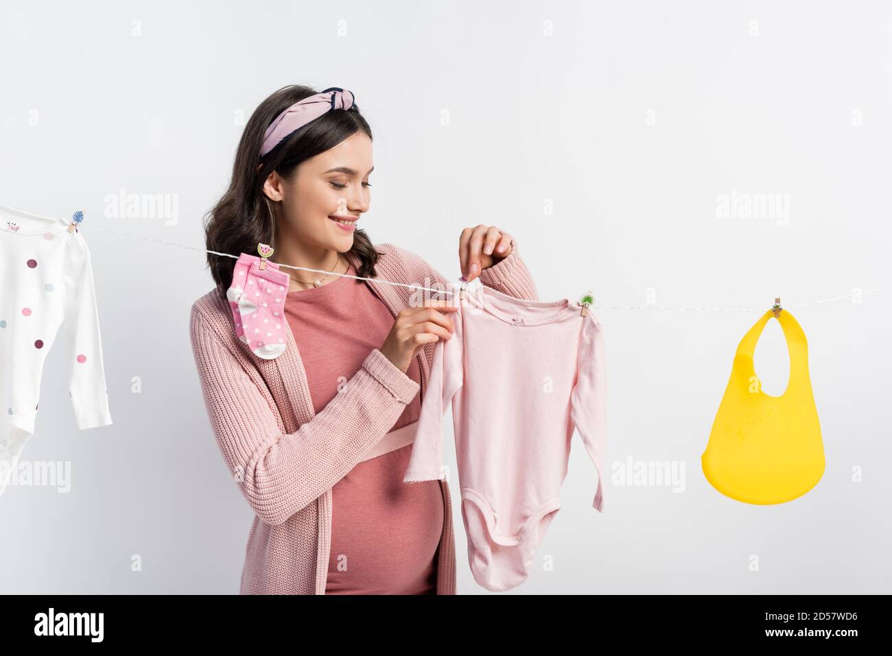 pregnant woman hanging baby clothes on clothing line isolated on white Stock Photo Alamy