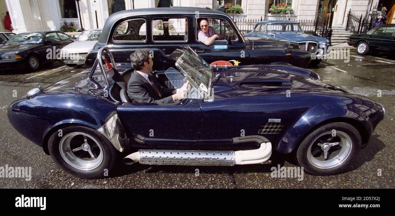 A Christie's employee driving a 1967 AC Cobra 427 Mk III pulls up along  side a London taxi June 3. The Cobra, one of the most powerful road-going  open sports cars ever