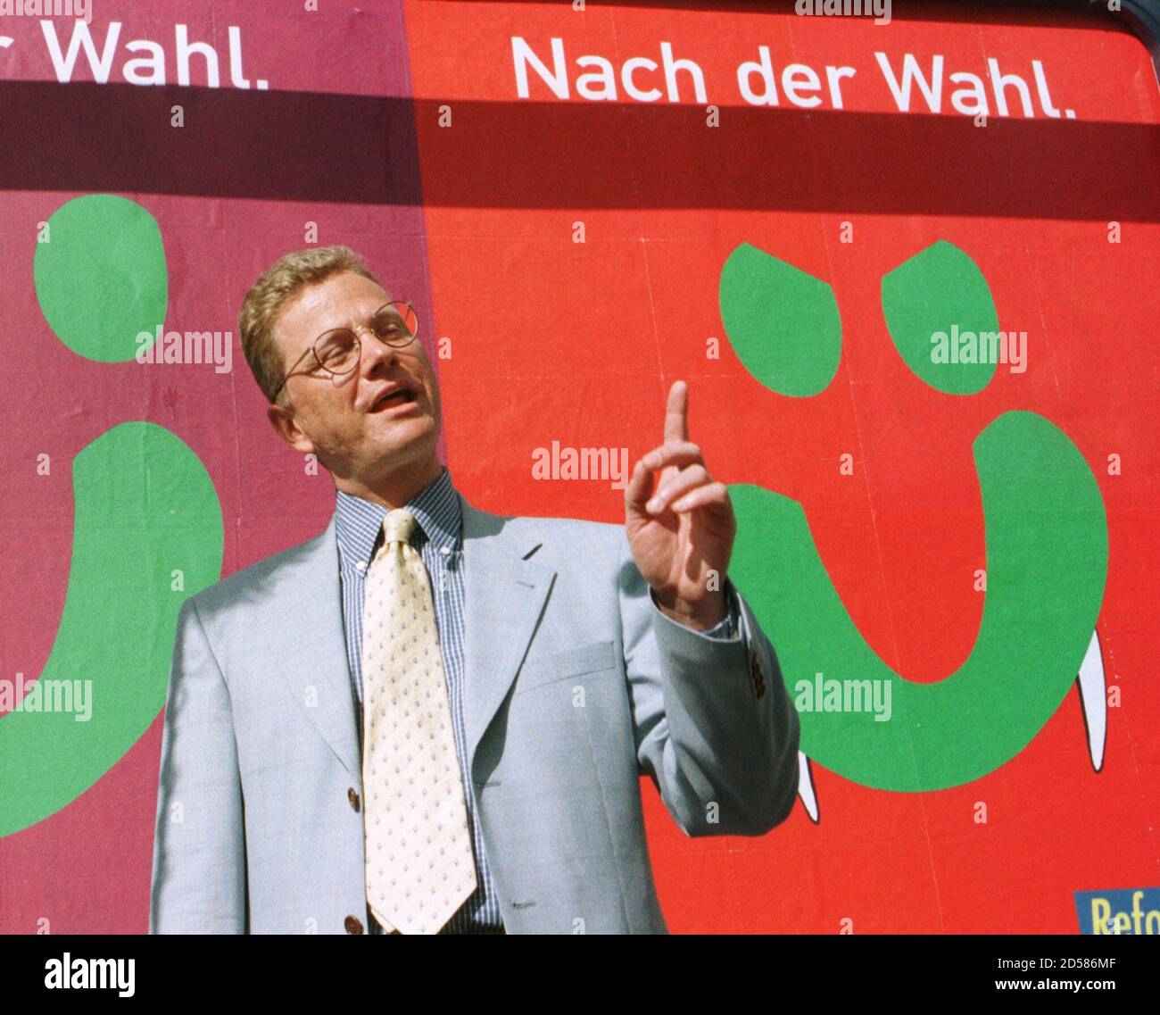 Guido Westerwelle, secretary general of the Free Liberal party FDP points at a new election campaign placard in Bonn June 8. The FDP' s new placard is a caricature of a campaign poster of the Greens party showing a smiling face with Dracula's teeth and reads 'after the elections' ('nach der Wahl'). Germany will elect a new Chancellor in the September 27 general elections. Stock Photo