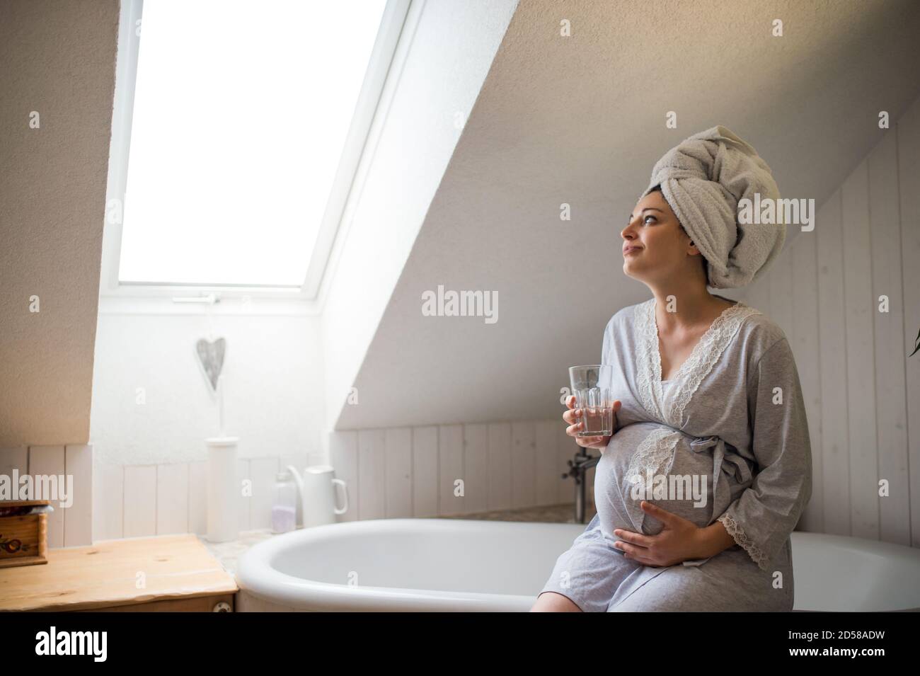Portrait of happy pregnant woman indoors in bathroom at home, holding ...