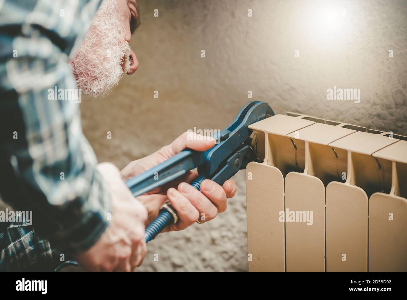 Repairman working on radiator with wrench Stock Photo - Alamy