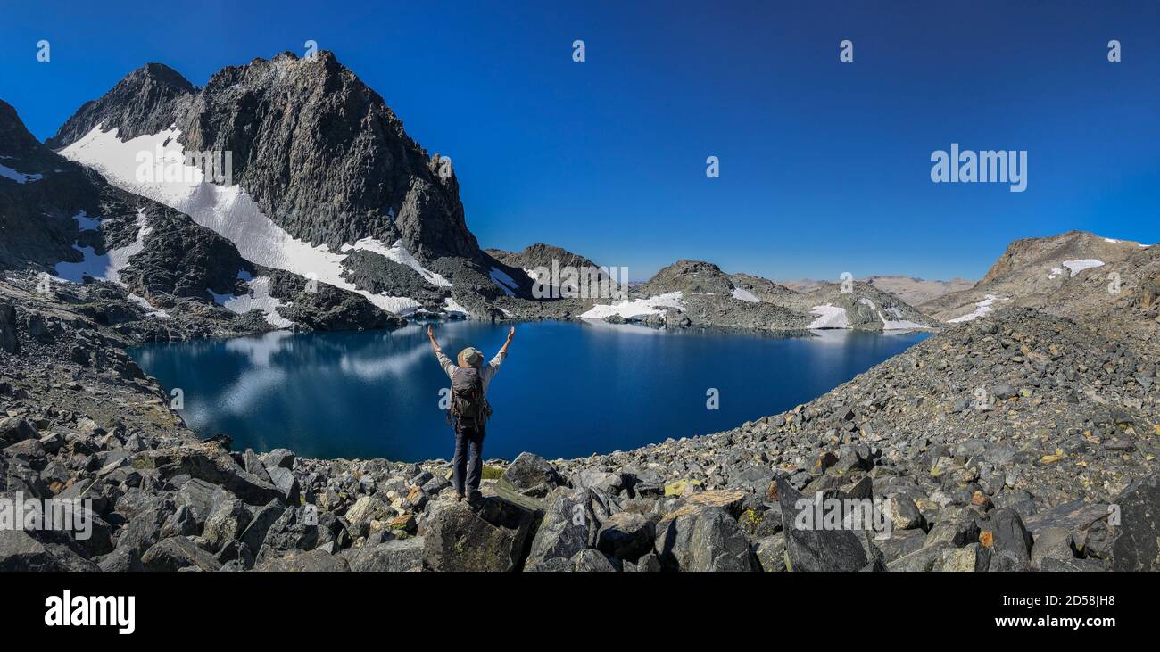 Hiker standing on rocks at Lake Catherine in front of Mount Ritter, Inyo National Forest, California, USA Stock Photo