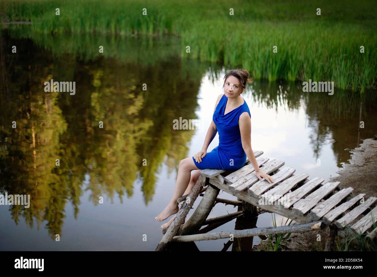 Woman sitting on a wooden pier by a lake, Bulgaria Stock Photo