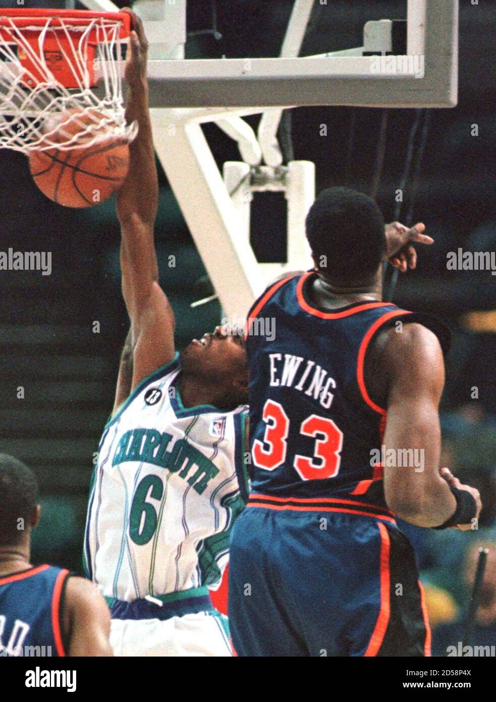 Charlotte Hornets' guard Eddie Jones hangs on the rim after dunking over  New York Knicks' center Patrick Ewing during first half NBA action,  February 7. This postponed game was rescheduled from December