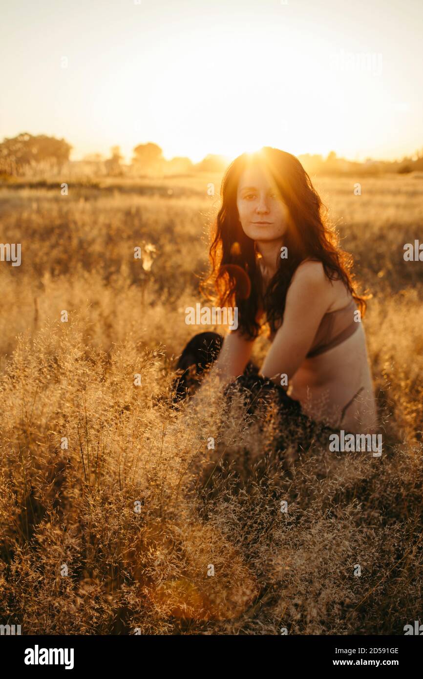Portrait of a Woman sitting in a field in summer at sunset, Russia Stock Photo