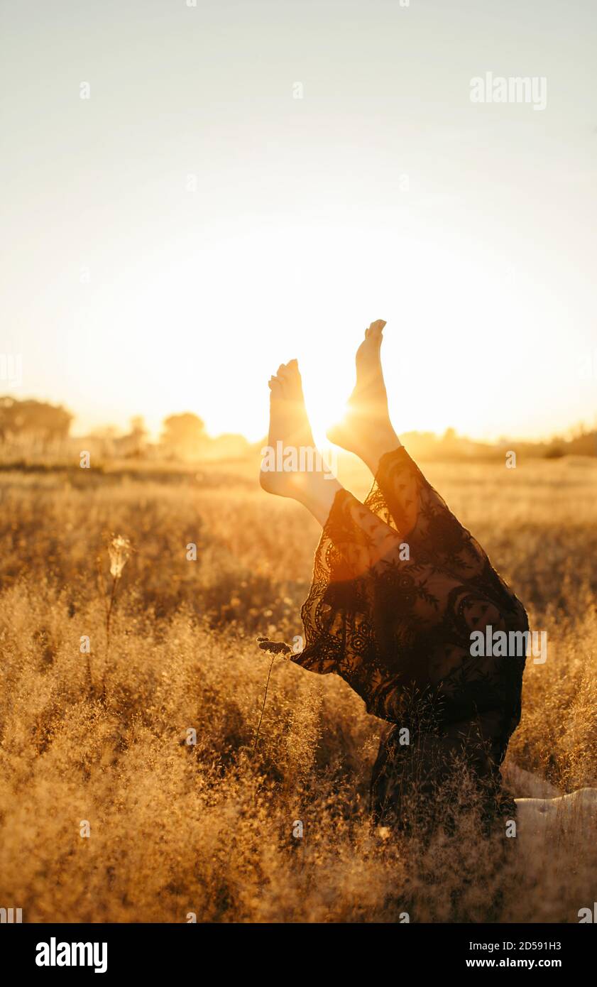 Woman lying in a field with her legs in the air at sunset, Russia Stock Photo