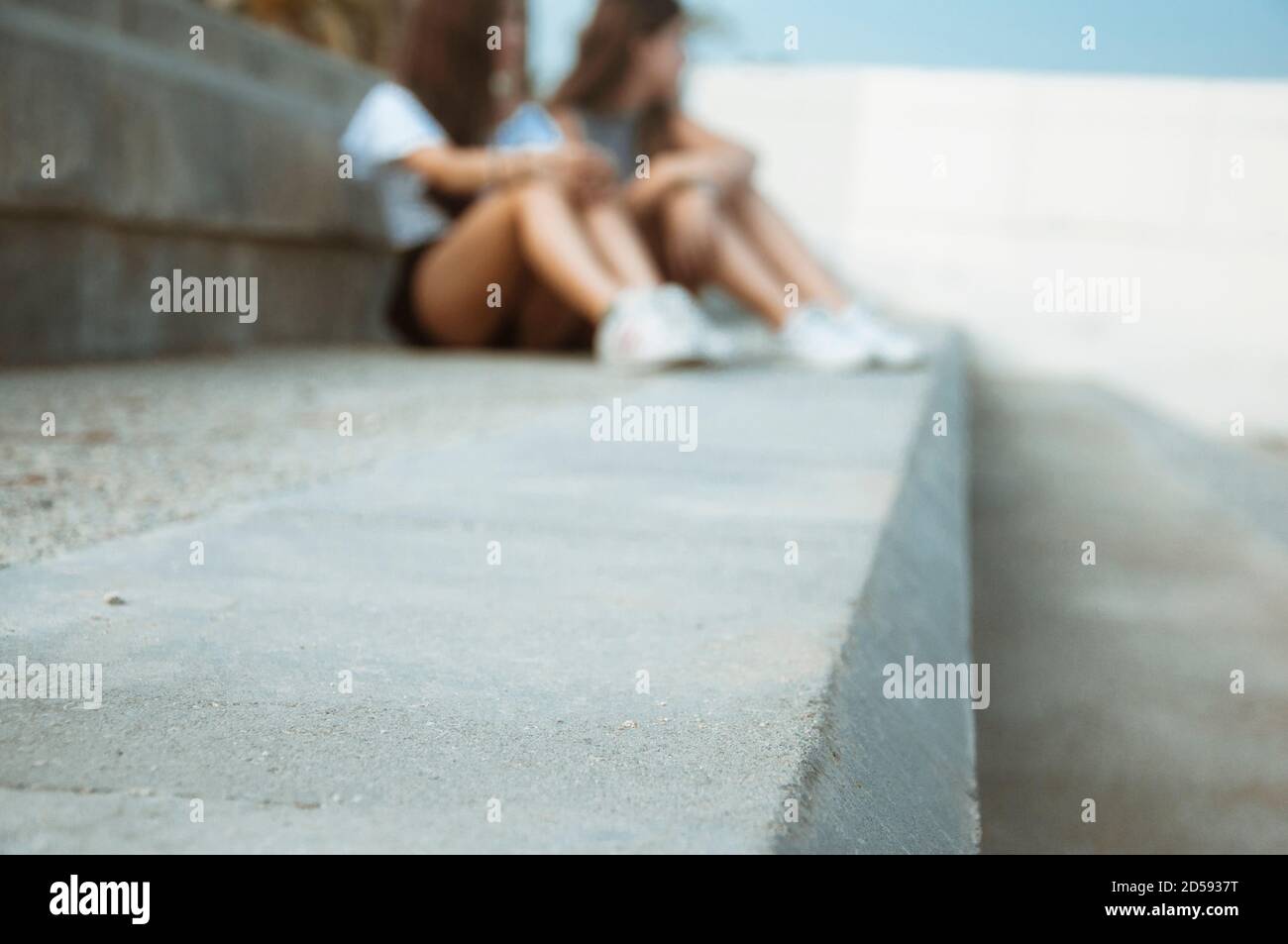 Mother and daughter sitting on a step waiting, Spain Stock Photo