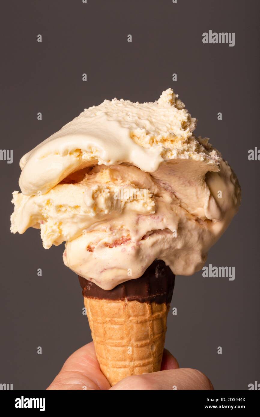 Raspberry ripple ice cream melting in a chocolate dipped cone. Stock Photo