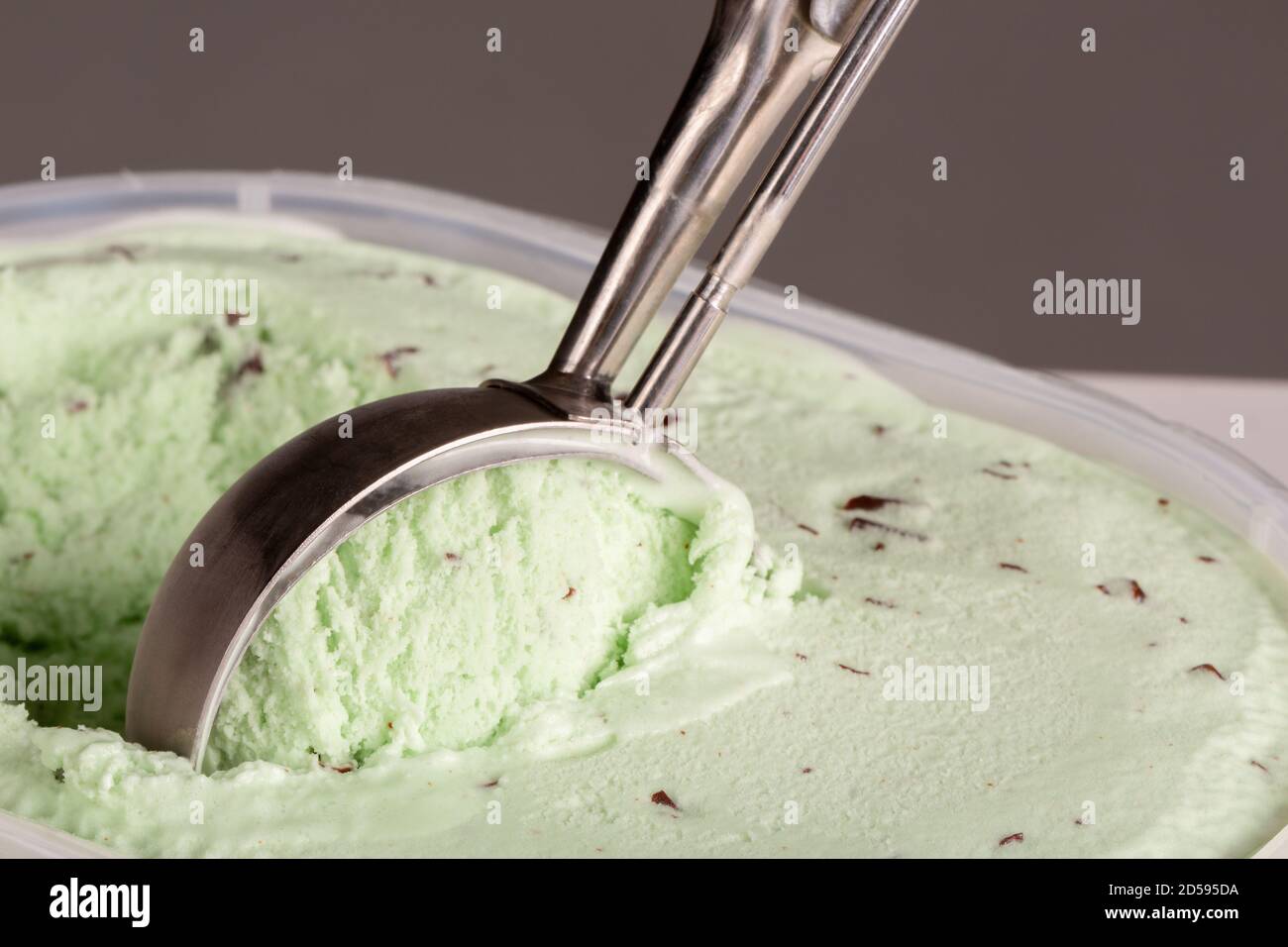 Close up of mint choc chip ice cream being scooped up by a mechanical scoop to be served. Stock Photo