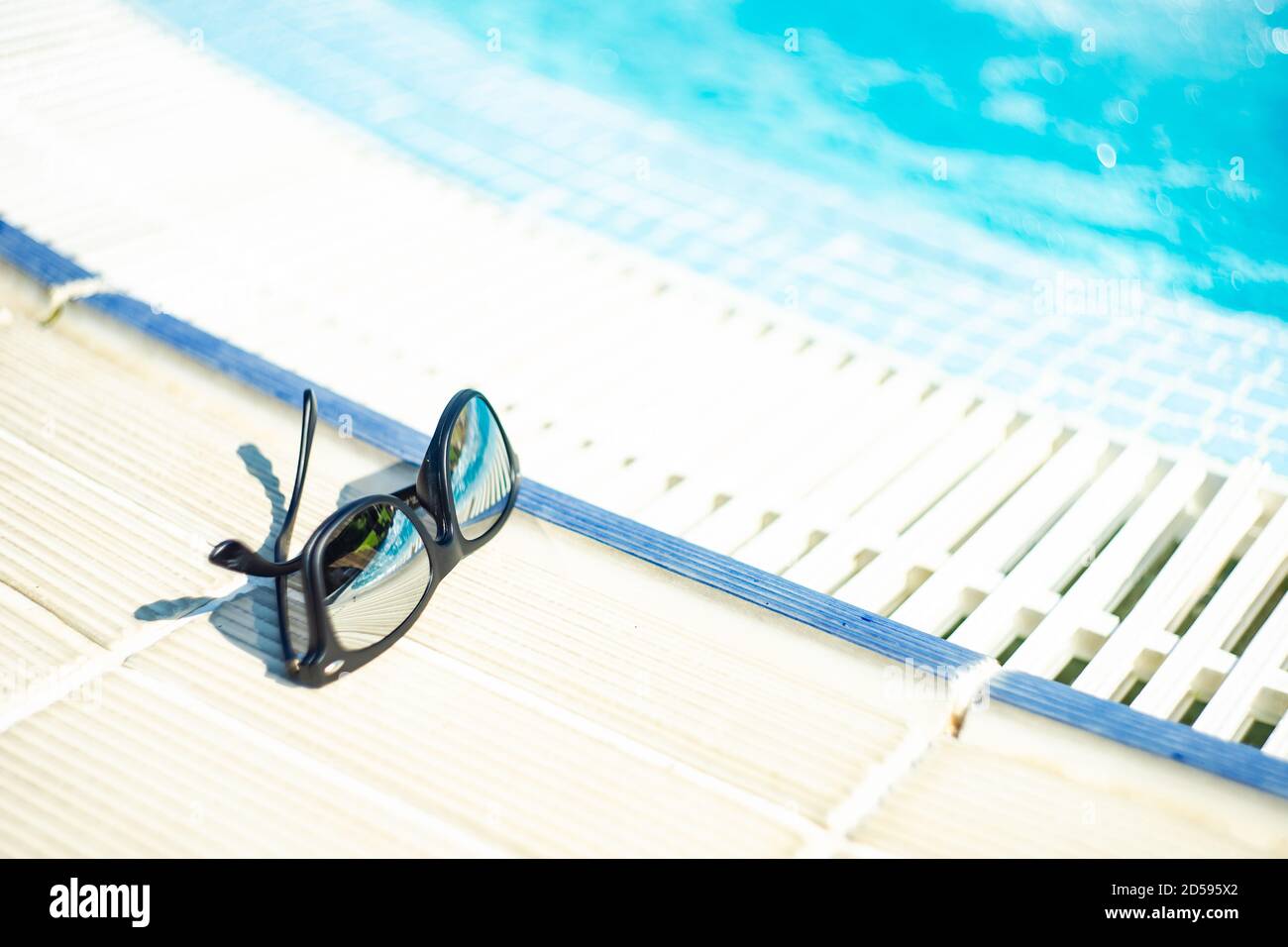 Sunglasses lying on the ground next to a swimming pool Stock Photo