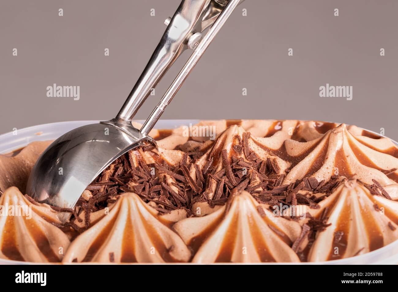 Close up of a mechanical ice cream scoop gathering up ice cream to be served. Stock Photo
