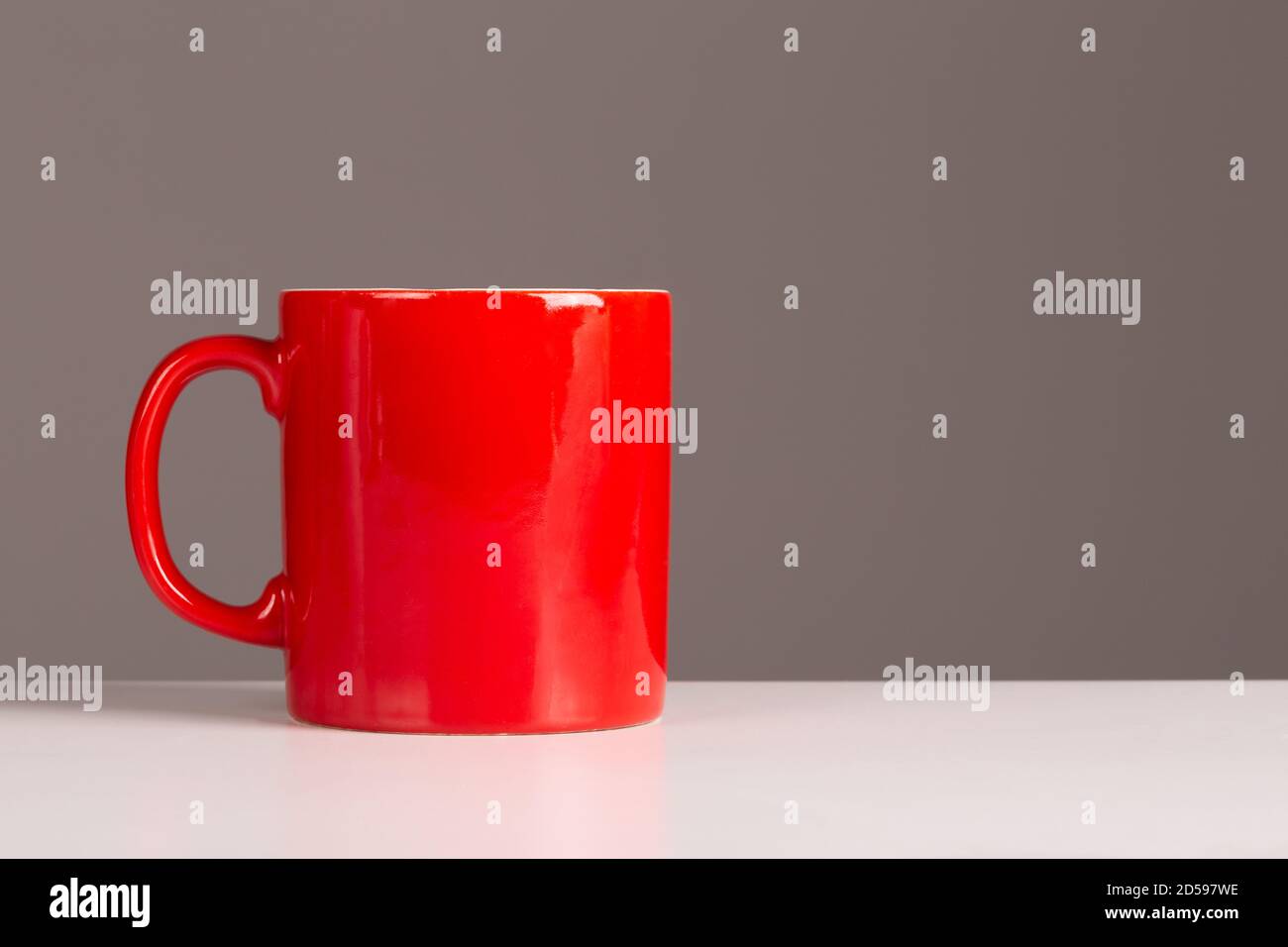 A bright red coffee or team mug on a neutral background with plenty of copyspace for designers. Stock Photo