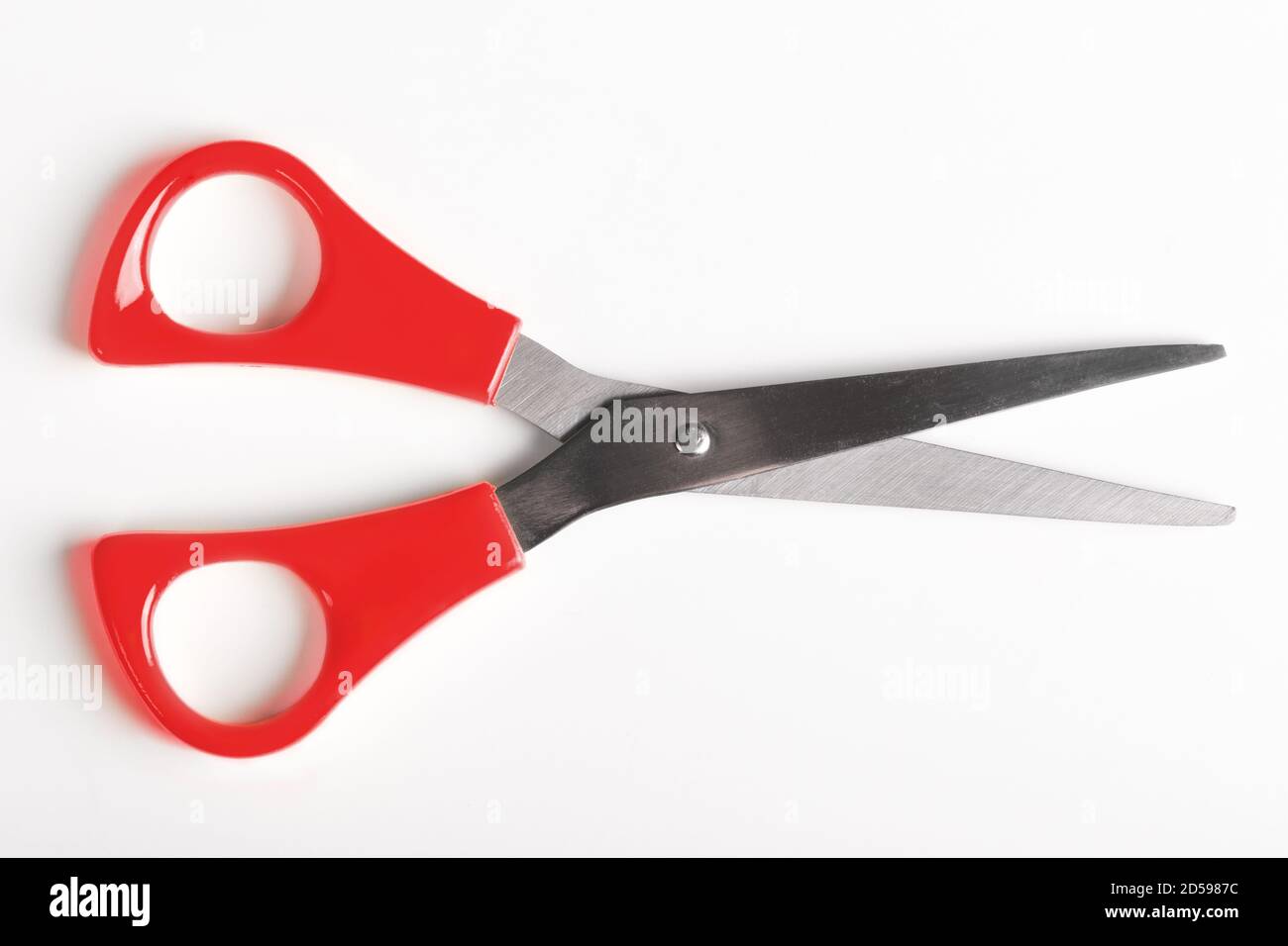 A pair of scissors with bright red handles, open as if about to cut. Stock Photo