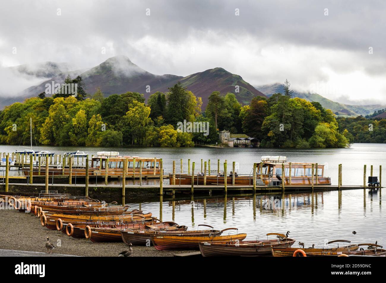 Rowing boats on Derwentwater by landing stages with Cat Bells beyond Derwent Isle in Lake District National Park in autumn. Keswick Cumbria England UK Stock Photo