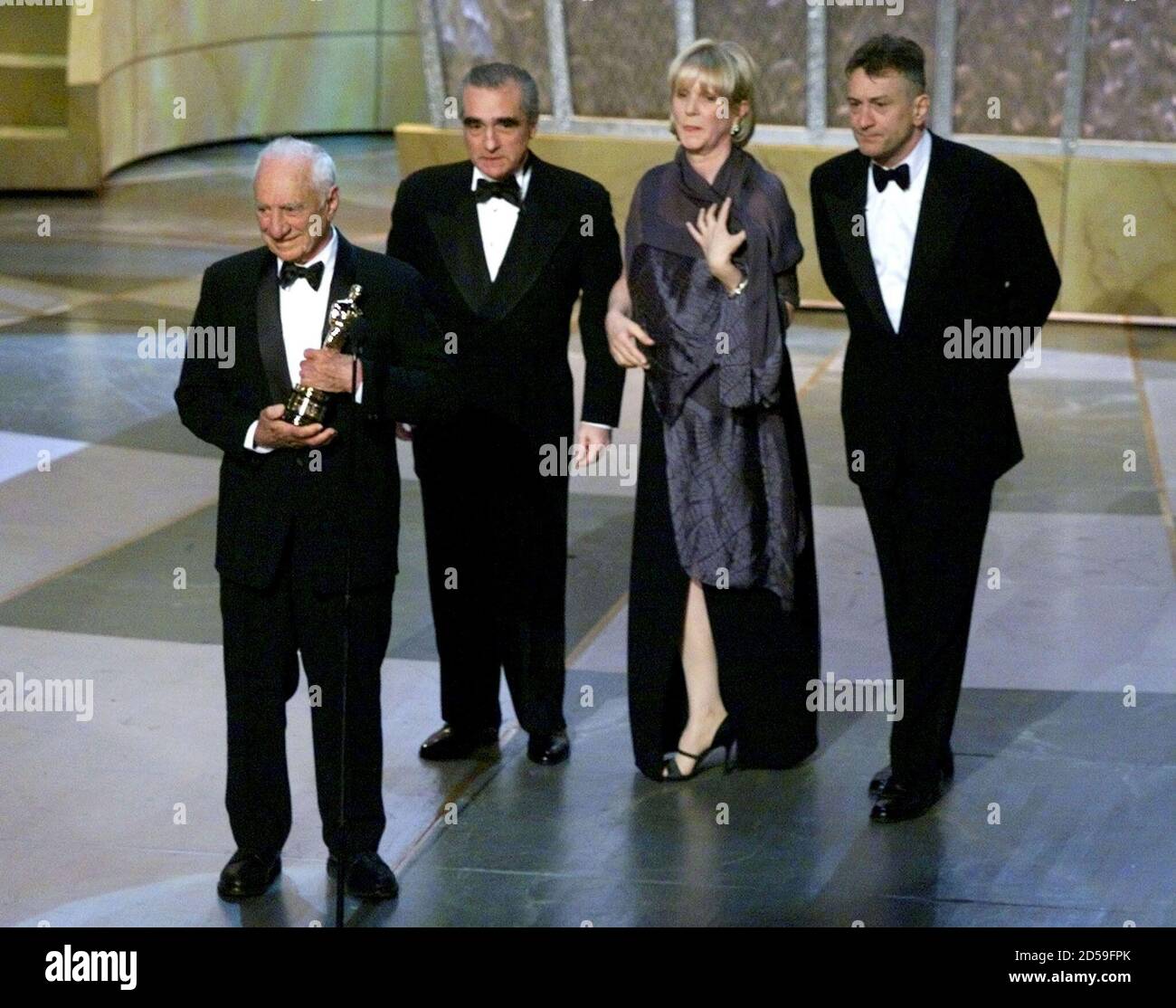 Elia Kazan (L) holds his Oscar after being presented the award by