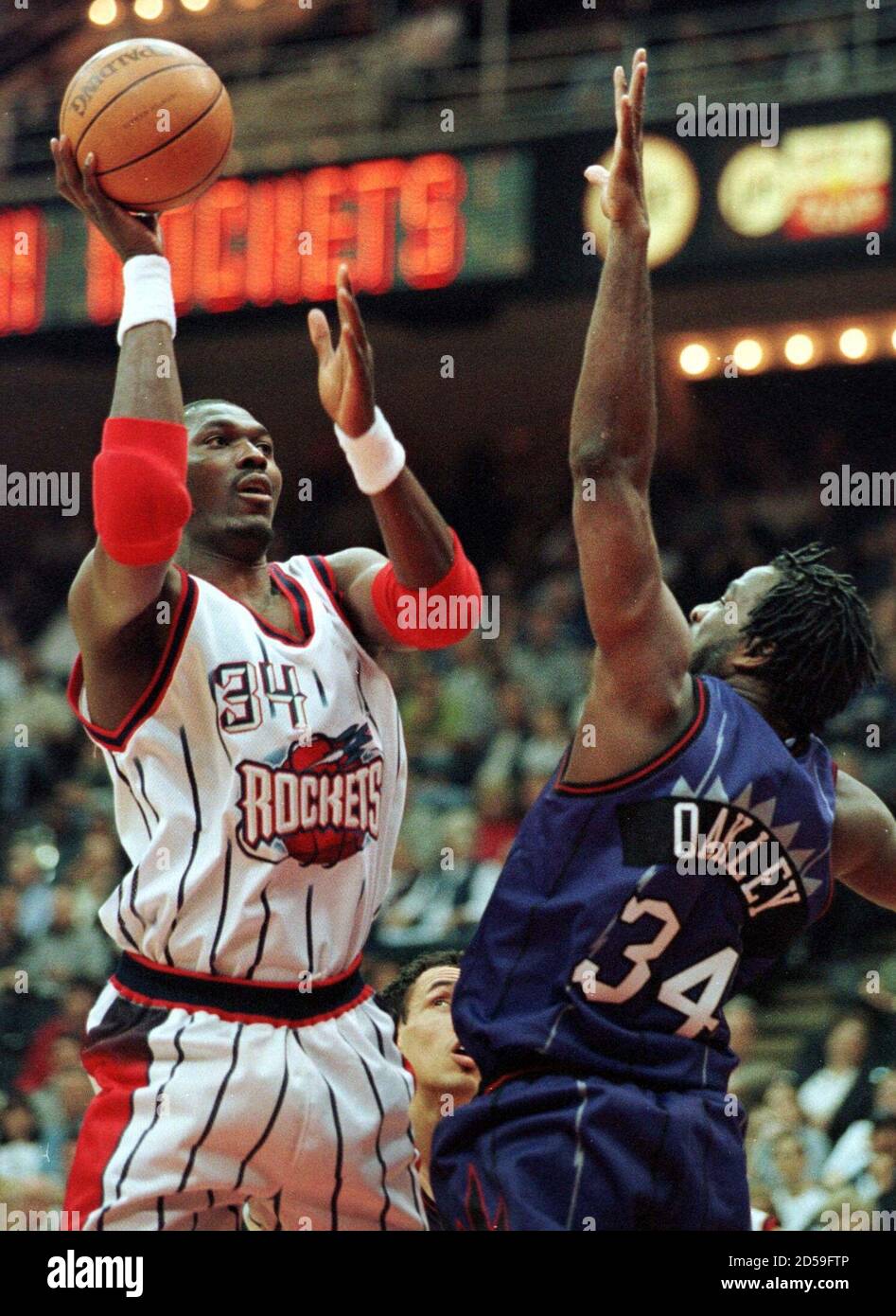 Houston Rockets Hakeem Olajuwon (L) shoots over the outstretched arms of  Toronto Raptors Charles Oakley during first half action, March 25. Olajuwon  was later ejected from the game after a confrontation with