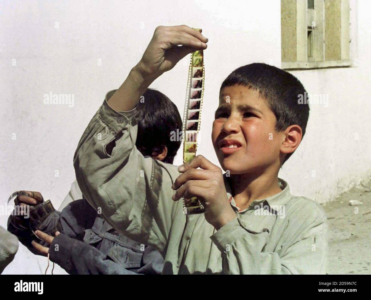 An Afghan boy examines a strip of movie film snatched from the flames of a bonfire set by the purist Islamic Taliban in front of Kabul's Zaynab cinema. The militia has banned music, cinema and television and imposed Islam's stern Shariah law on the Afghan capital. Photo taken 14OCT96. Stock Photo