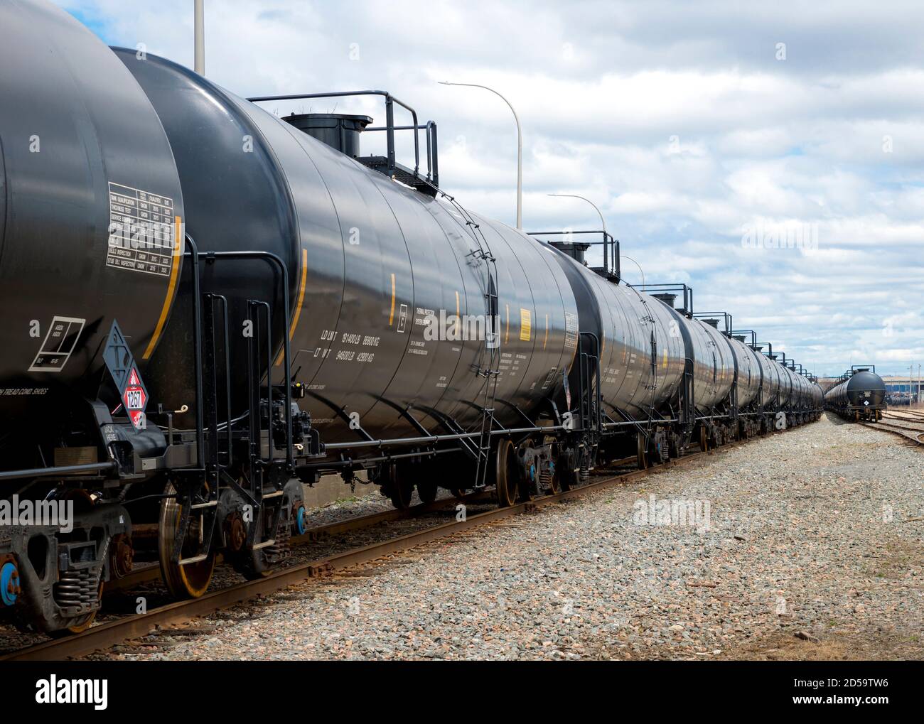 Black railway tanker cars of the type used to transport petroleum products. Several cars visible on two separate sets of tracks. Identification markin Stock Photo