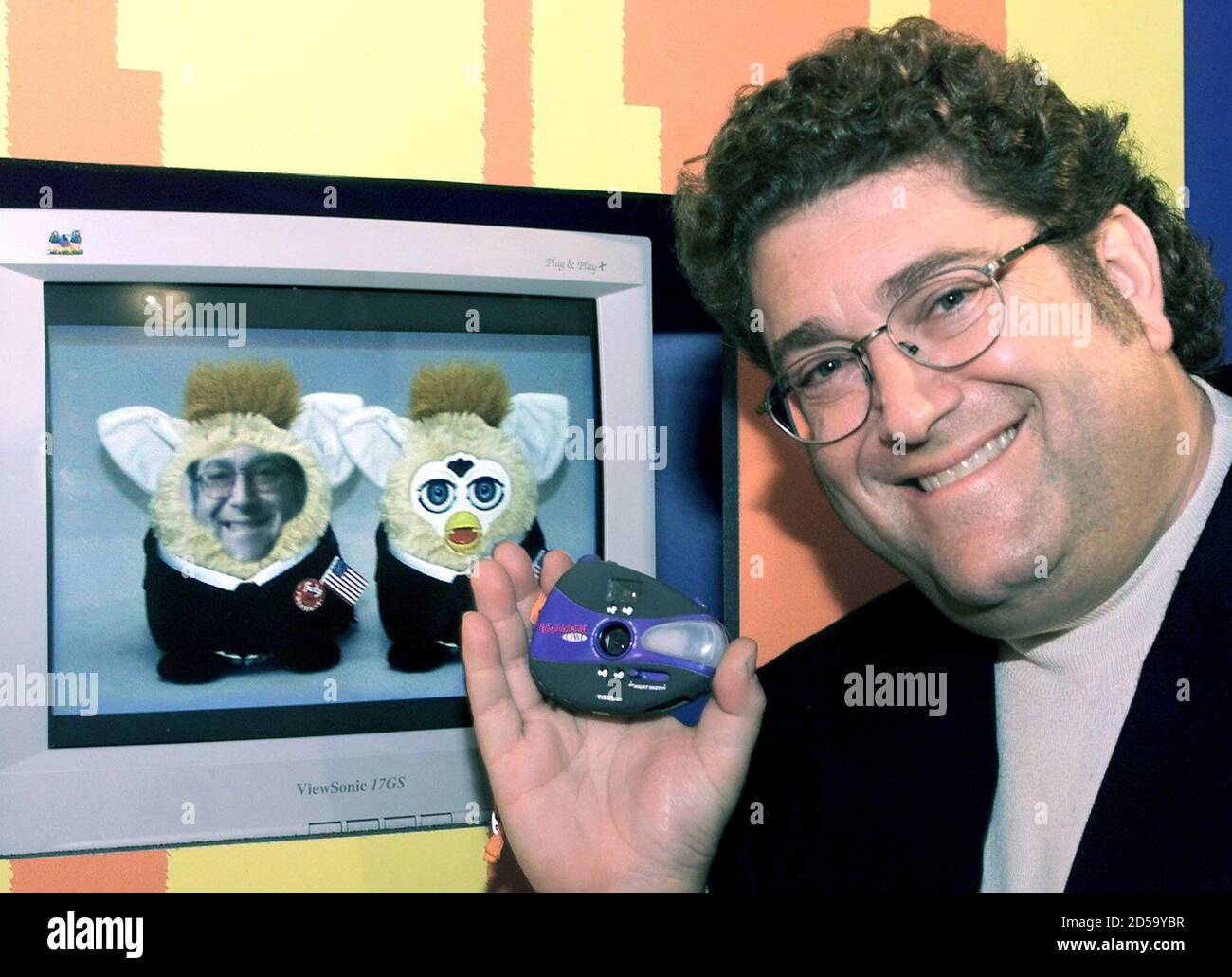 https www alamy com tiger electronics coo roger schiffman holds the new yahoo cam a palm sized digital camera capable of taking photographs and posting them to the world wide web in the tiger showroom february 12 in new york where he was preparing for the opening of the american international toy fair on february 14 a photo made with the camera of schiffman has been morphed into one of two furby toys l on the computer screen using the software that comes with the camera the 60 approximate retail camera can take and store up to 12 color photos and the infrared flash allows photos in complete darkness w image381920443 html