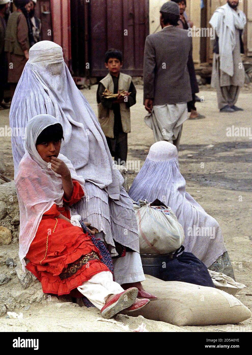 Afghan women, wearing burqas, covering their faces sit next to a young girl in this city 60km north of Kabul October 2. The radical Taliban militia that conquered Kabul last week has begun enforcing a purist proud of Islam that has struck fear into many educated people, especially women. Stock Photo