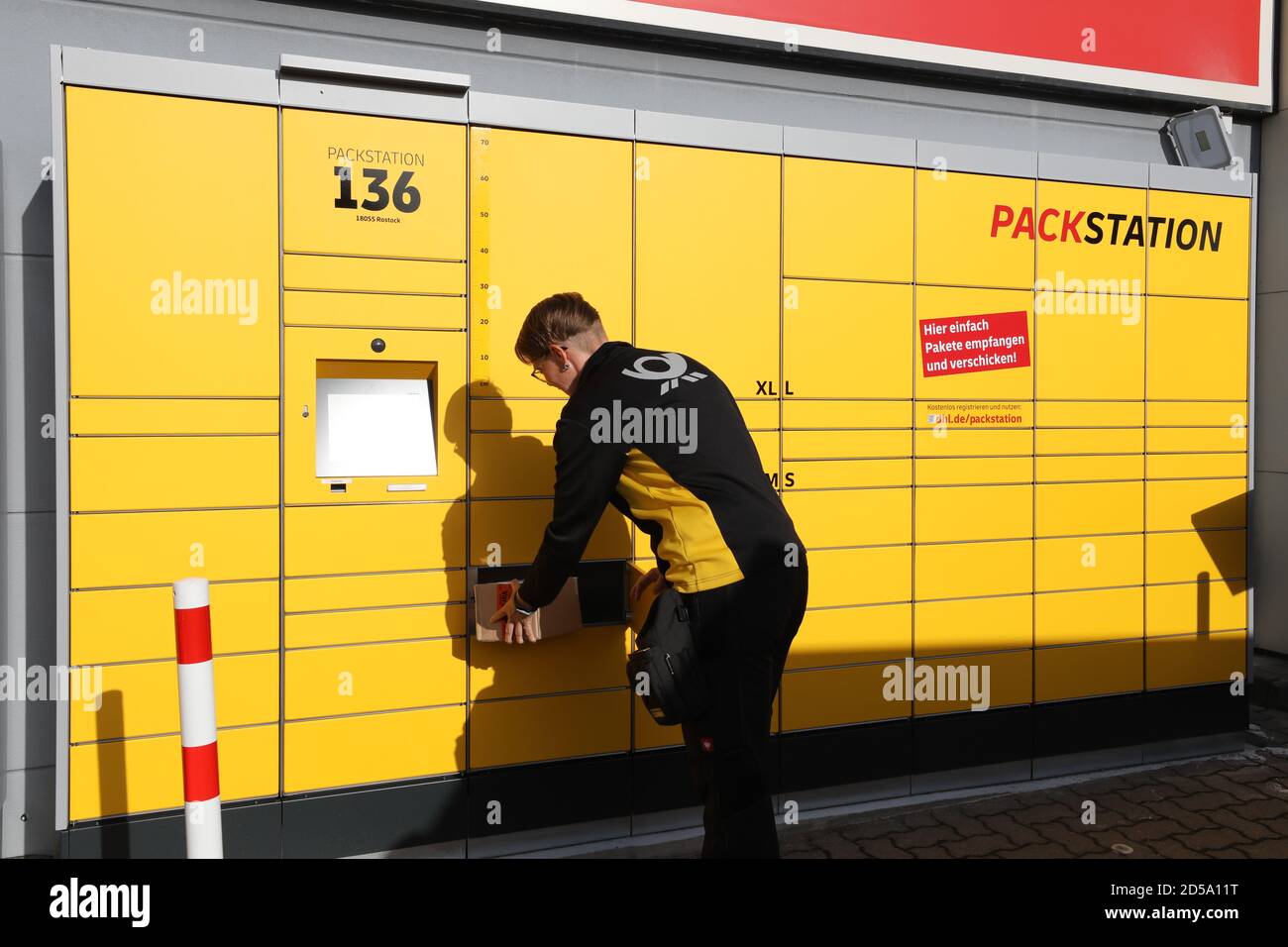 Rostock, Germany. 13th Oct, 2020. After the official launch of the 6000th  DHL Packstation, DHL employee Manuela Knod drops off a parcel. DHL plans to  have a total of 7000 Packstations in