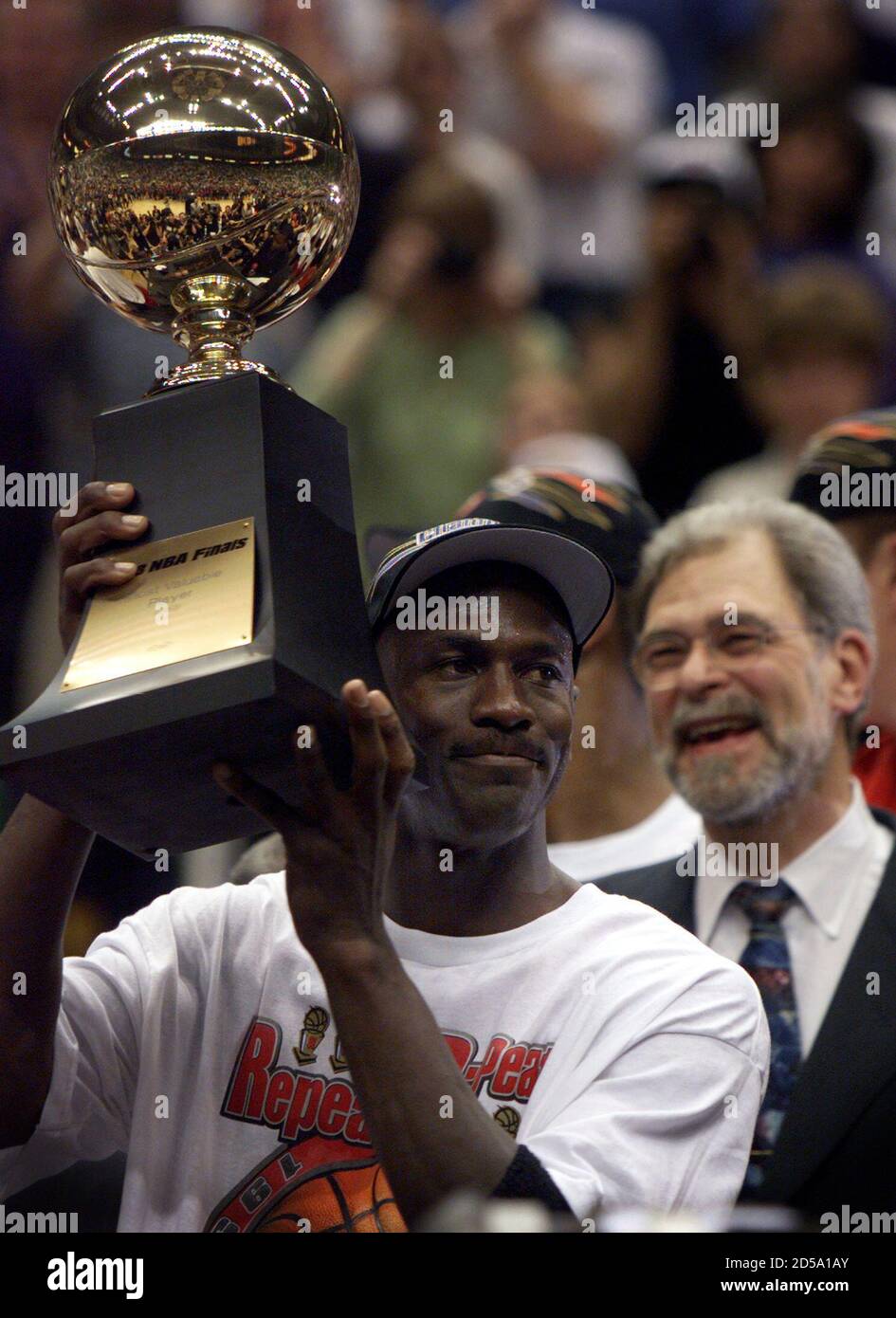 Chicago Bulls Michael Jordan holds up the MVP trophy in front of coach Phil Jackson after the Bulls defeated the Utah Jazz 87-86 win the NBA championship June 14, 1998. REUTERS/Mike