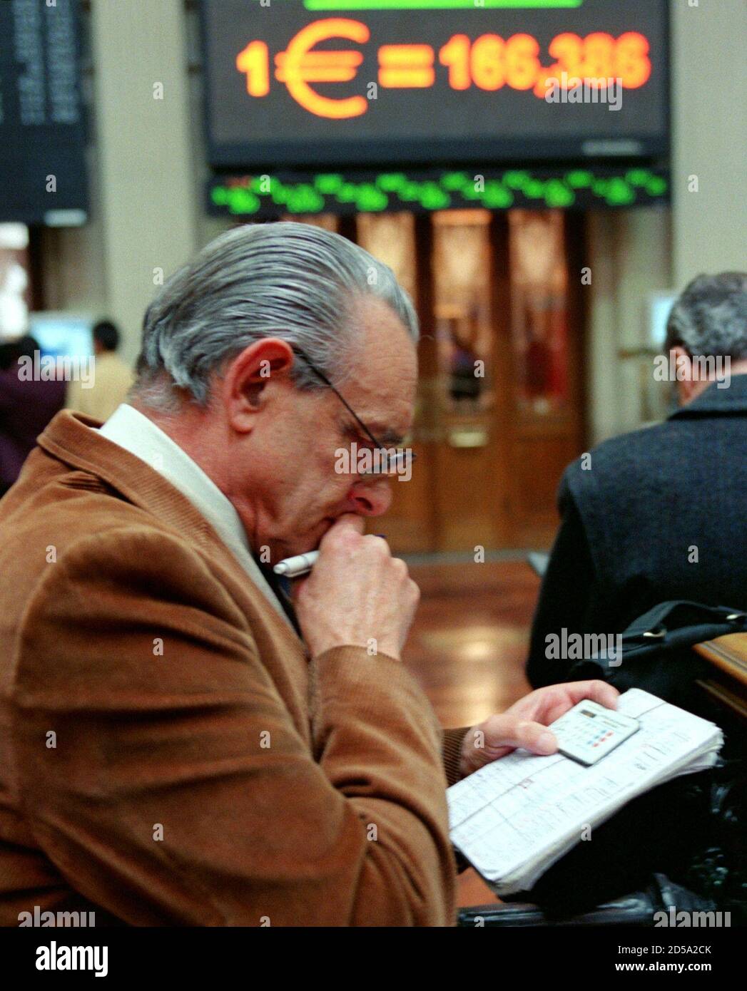 A man uses a calculator in front of a pannel showing the euro conversion  rate for the peseta at Madrid's Bourse on the first day of trading in euros  January 4. Spanish